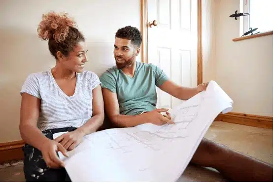Young couple looking at a floor plan to redecorate.