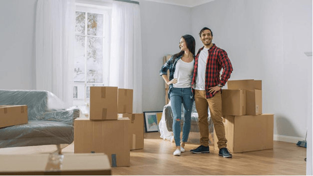 Young couple standing in an empty room with moving boxes.