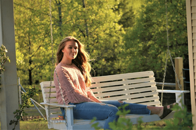 Woman swinging on a front porch swing.