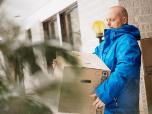 Man in winter coat moving a box out of a house.