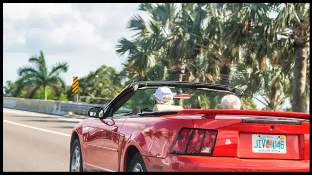 Elderly couple driving down the street in a convertible in Florida.