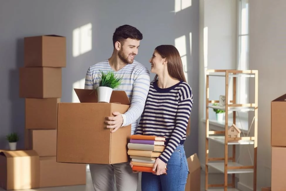 A couple carrying moving boxes into their new home