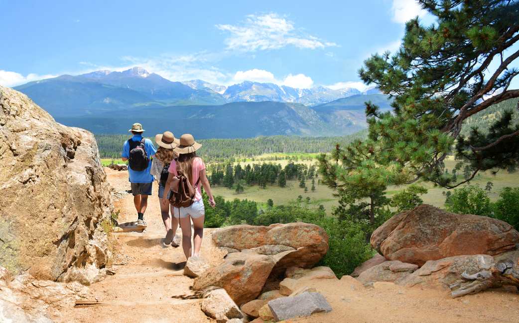 A family walks on a hike through the Rocky Mountains.