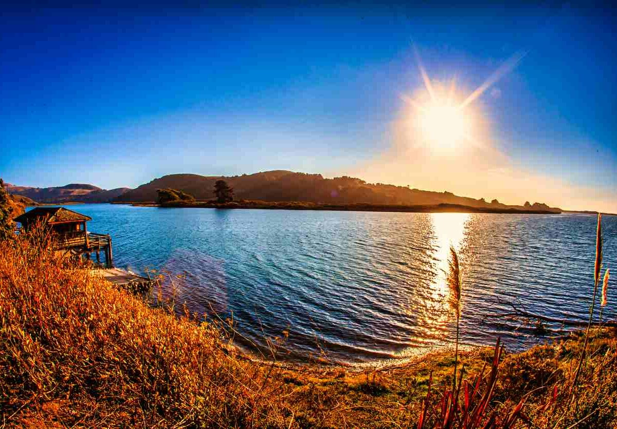 a serene lake with a dock under the radiant sun