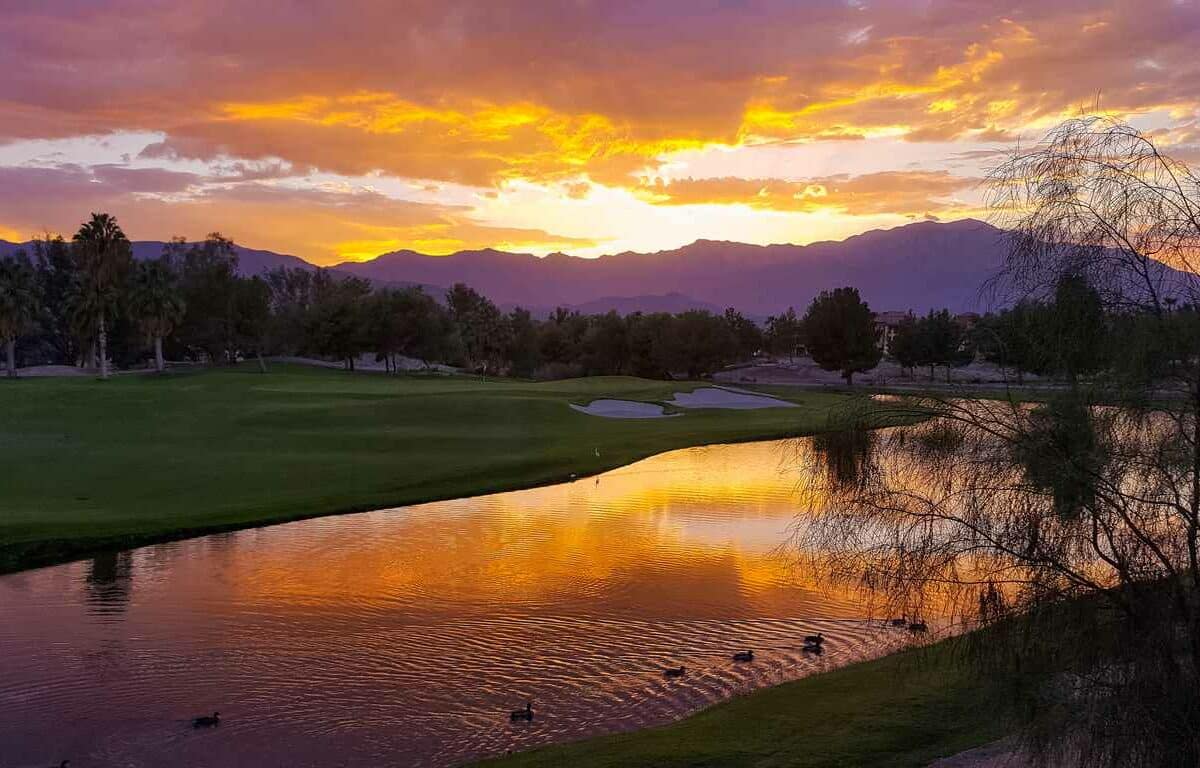 A pond in front of the mountains at sunset