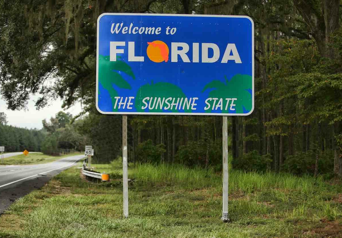 A photograph of a road sign that reads “Welcome to Florida the sunshine state”