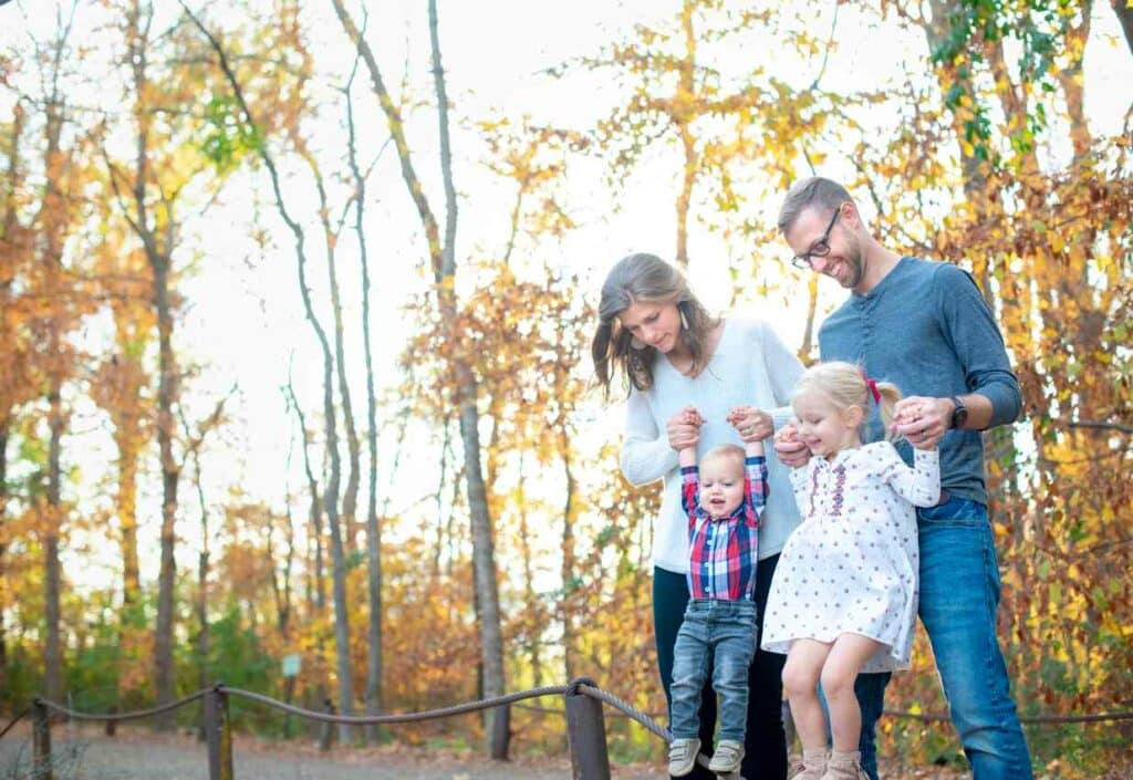 A family of four holding hands on a road that goes through a forest in Texas.