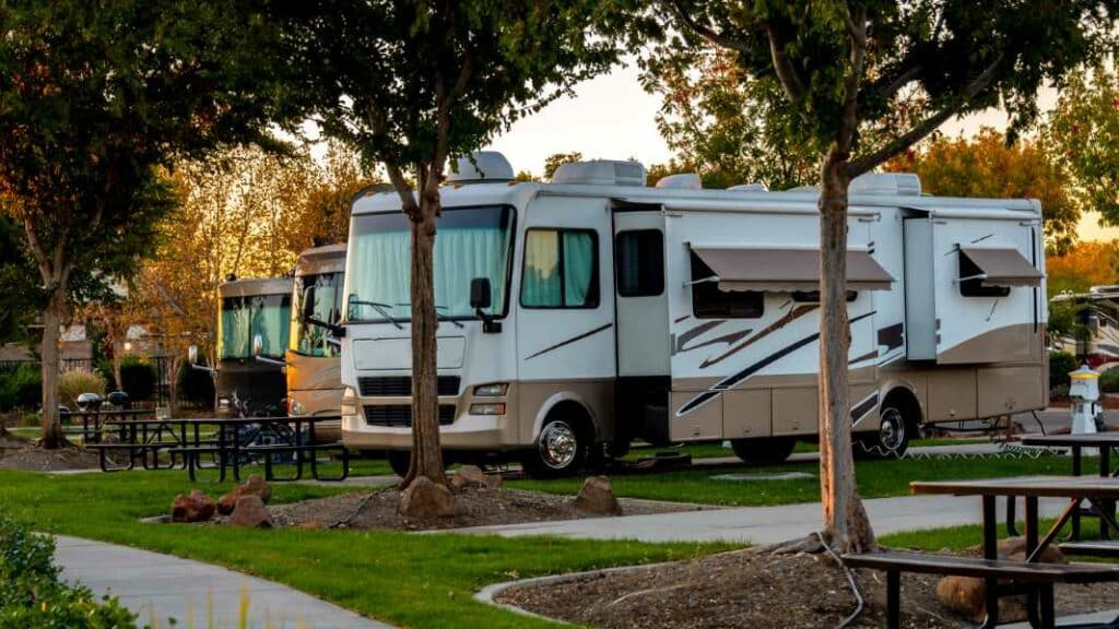 Several RVs parked in an RV campsite underneath trees