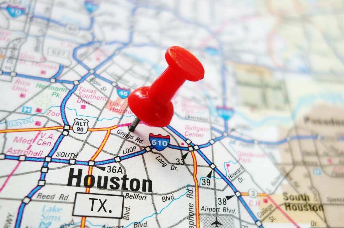A paper map of Houston with a red pin marking the spot of the city.