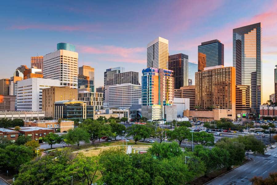 Downtown Houston, Texas, with skyscrapers and trees around a park in the city at sunset. 