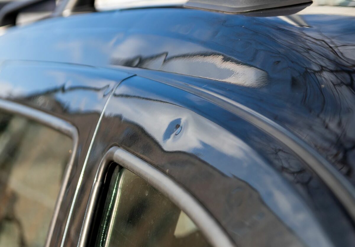 Close-up of a car roof with many hail damage dents.