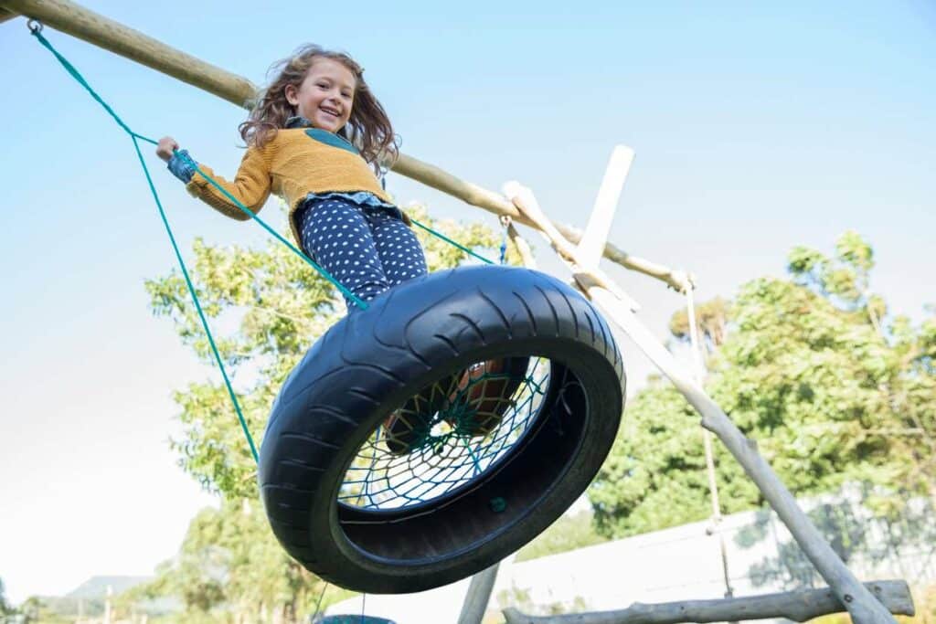 A girl swinging on a tire swing at her home