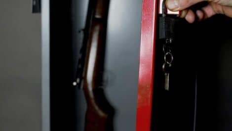 A hunting rifle stored inside a locked gun safe.